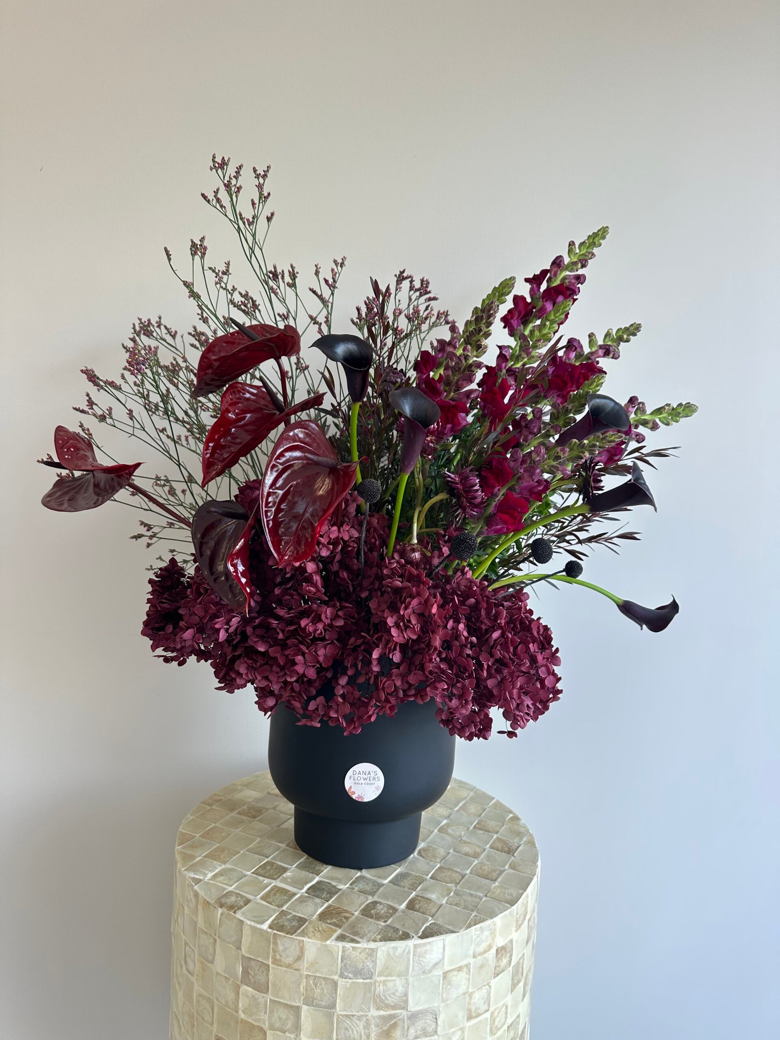 Dark burgundy flower arrangement with premium seasonal blooms in deep red and wine tones